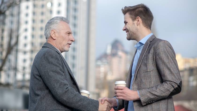 Young businessman and his mature mentor shaking hands