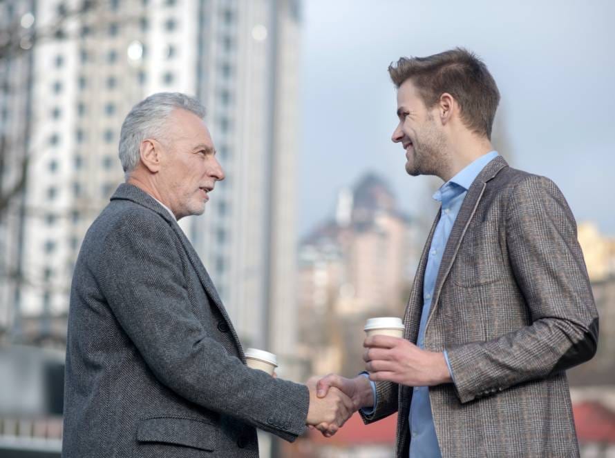 Young businessman and his mature mentor shaking hands