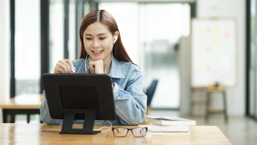 Young female student learning online using tablet.