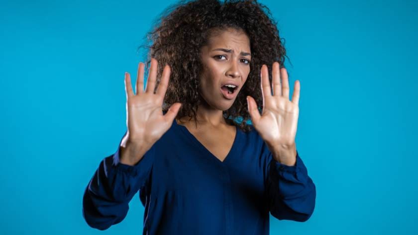 Angry annoyed woman raising hands up to say no stop